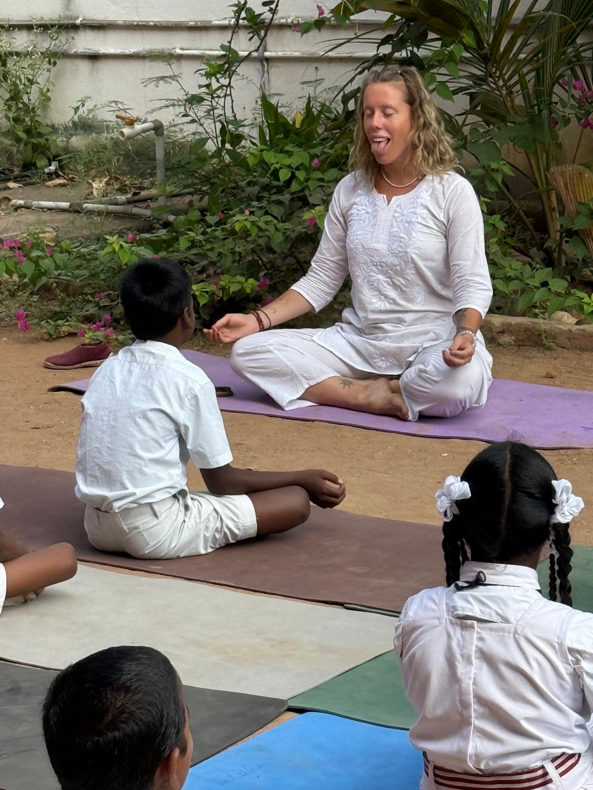 Deva guiding children through a calming breath practice outdoors
